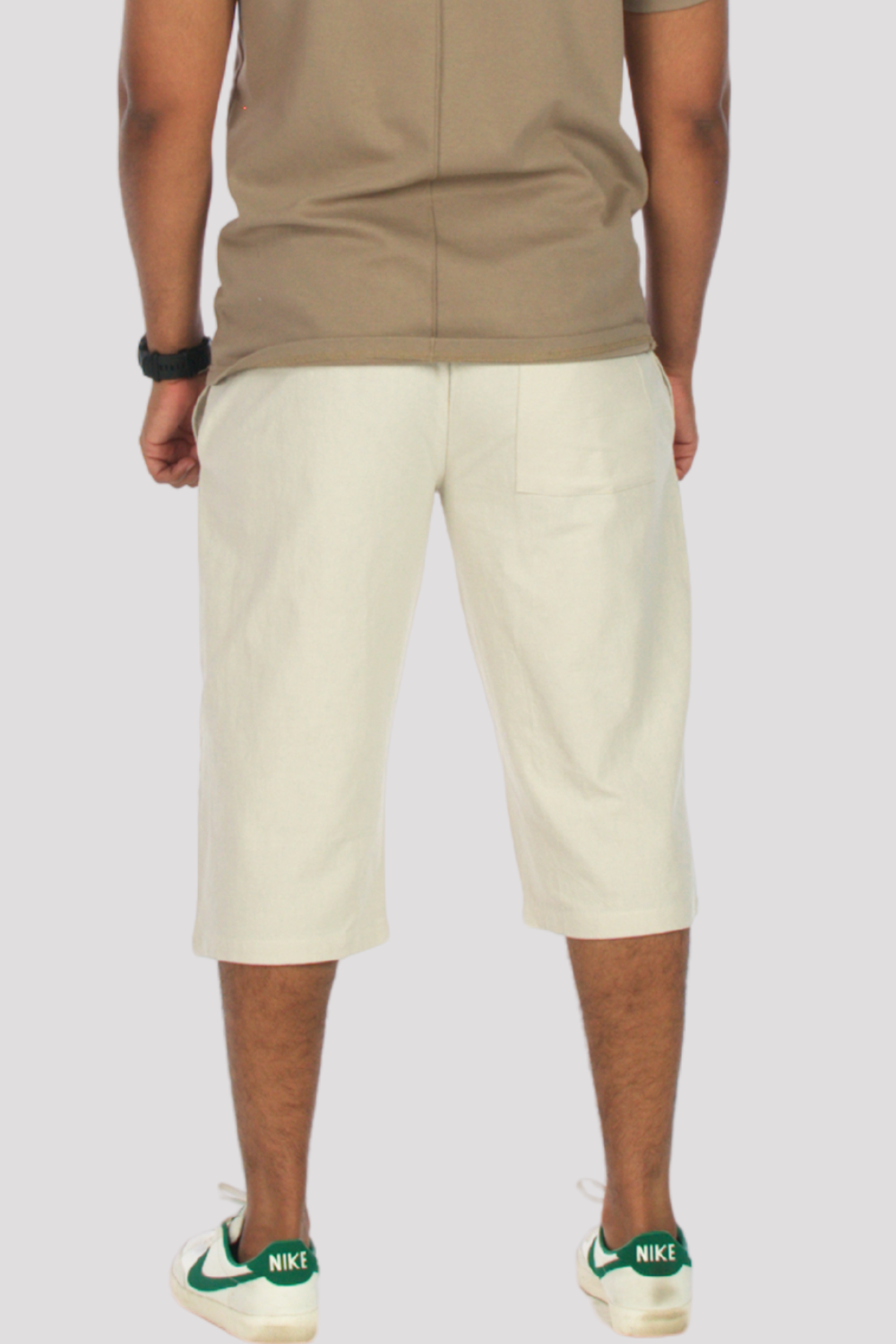 Person wearing stone 3/4 shorts and a taupe polo shirt on a plain background