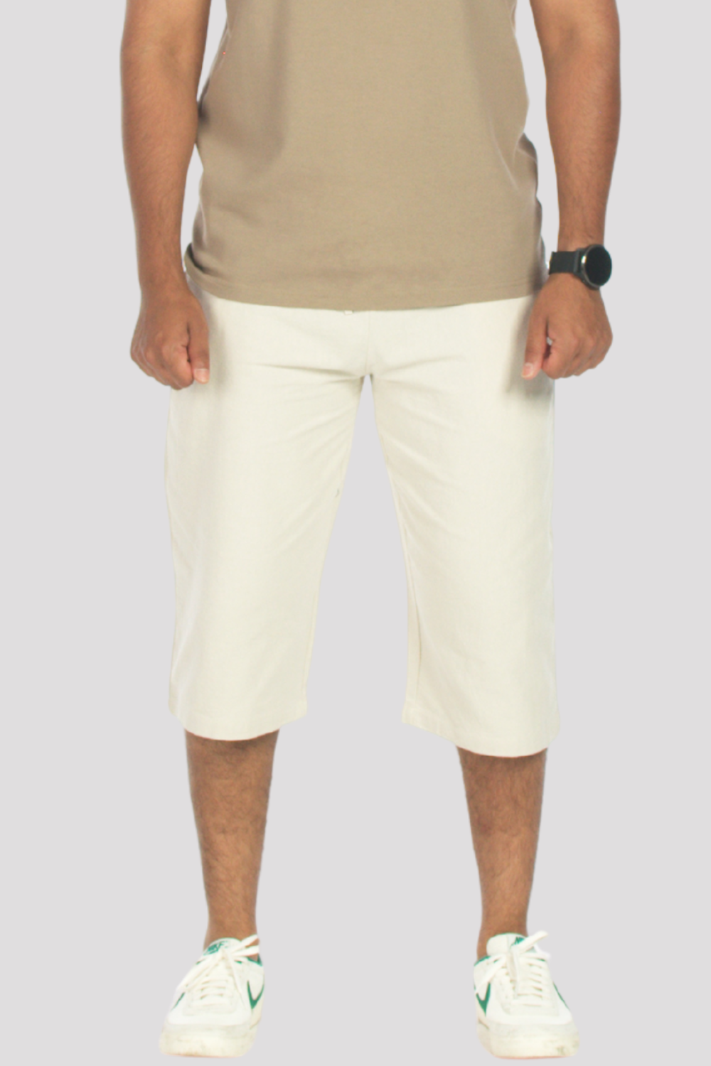 Person wearing a taupe polo shirt and stone 3/4 shorts on a plain background