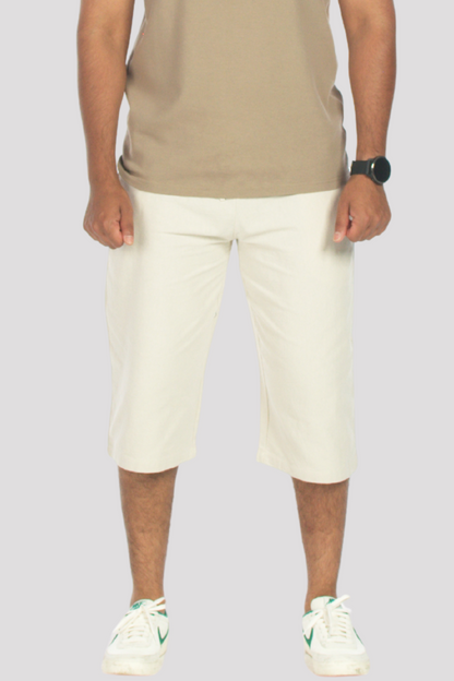 Person wearing a taupe polo shirt and stone 3/4 shorts on a plain background