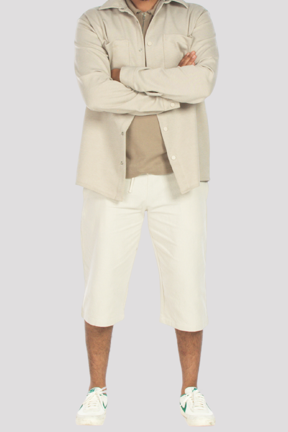Person wearing a beige shirt and stone 3/4 shorts on a light gray background